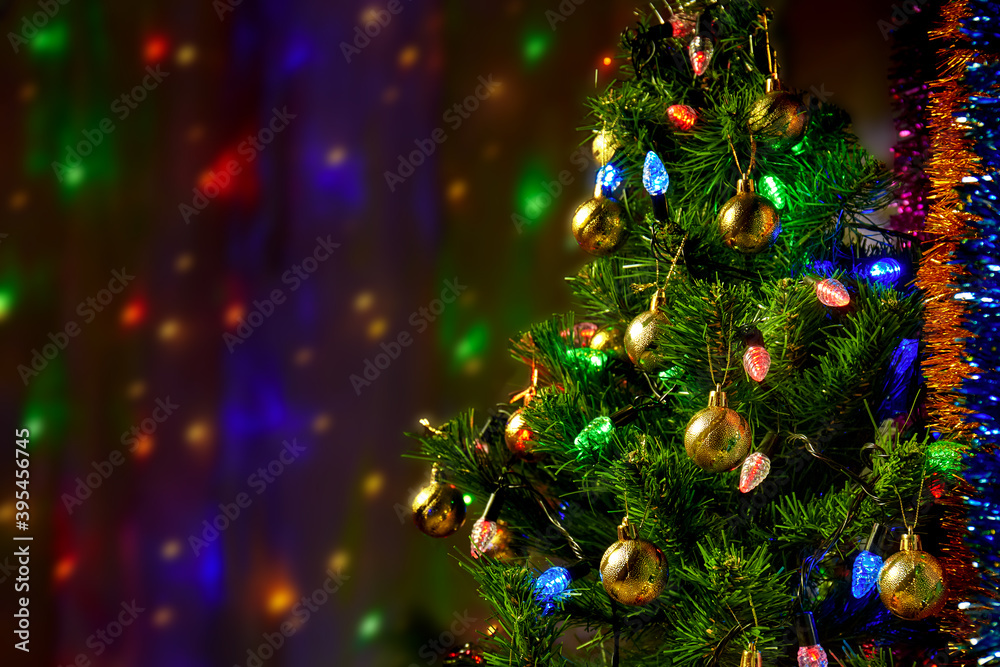 Decorated green Christmas tree on a semi-blurred background with bright lights