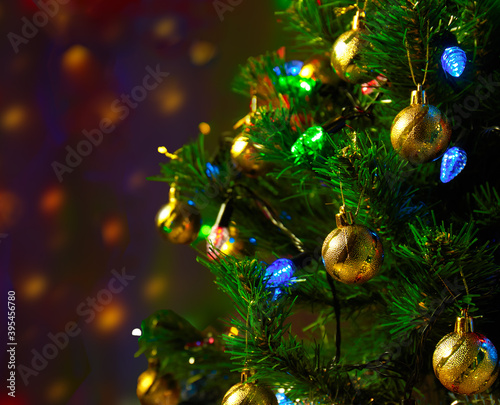Christmas tree decorated with blue and green lights on a semi-blurred background of lights