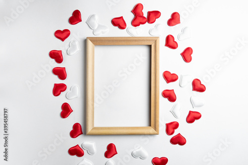 Mockup wooden frame and decorative red and white hearts on a white background. An idea for your romantic and holiday photos. Holiday text in a frame. Romantic framed photos © Alexandr