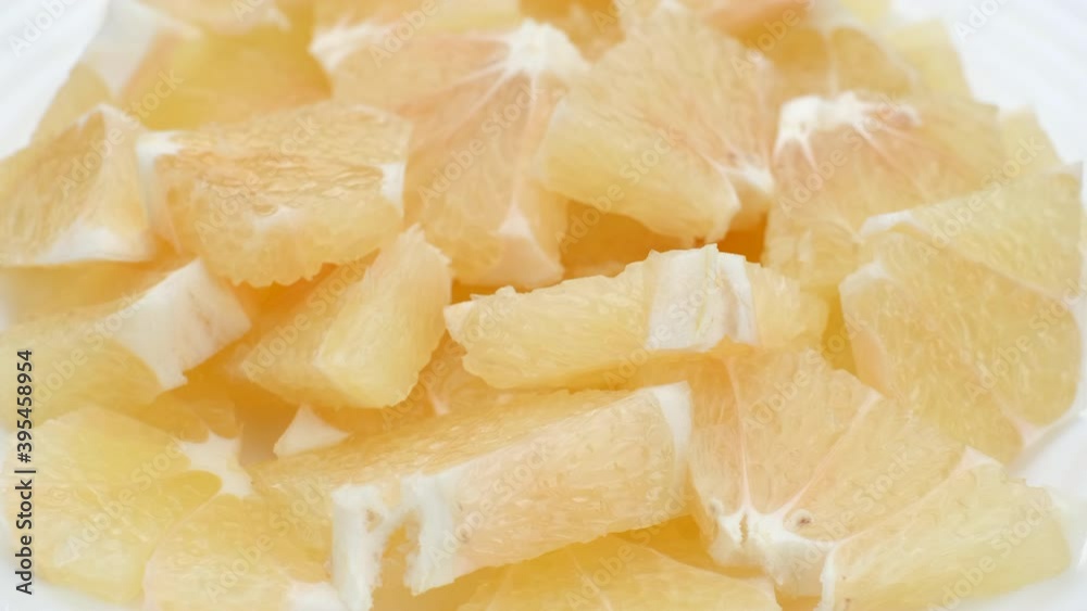chopped citrus sweetie fruit in white plate, rotating
