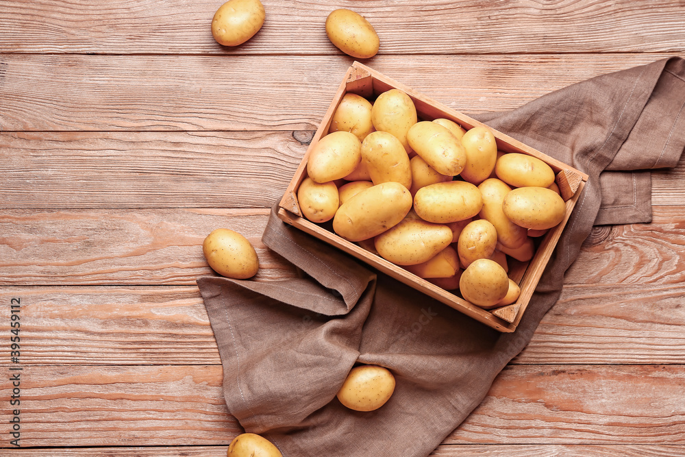 Wooden crate with raw potatoes on wooden table Wooden crate with raw potatoes on wooden table