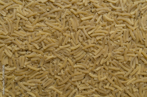 Background of finely chopped uncooked arcuate noodles scattered on a flat surface