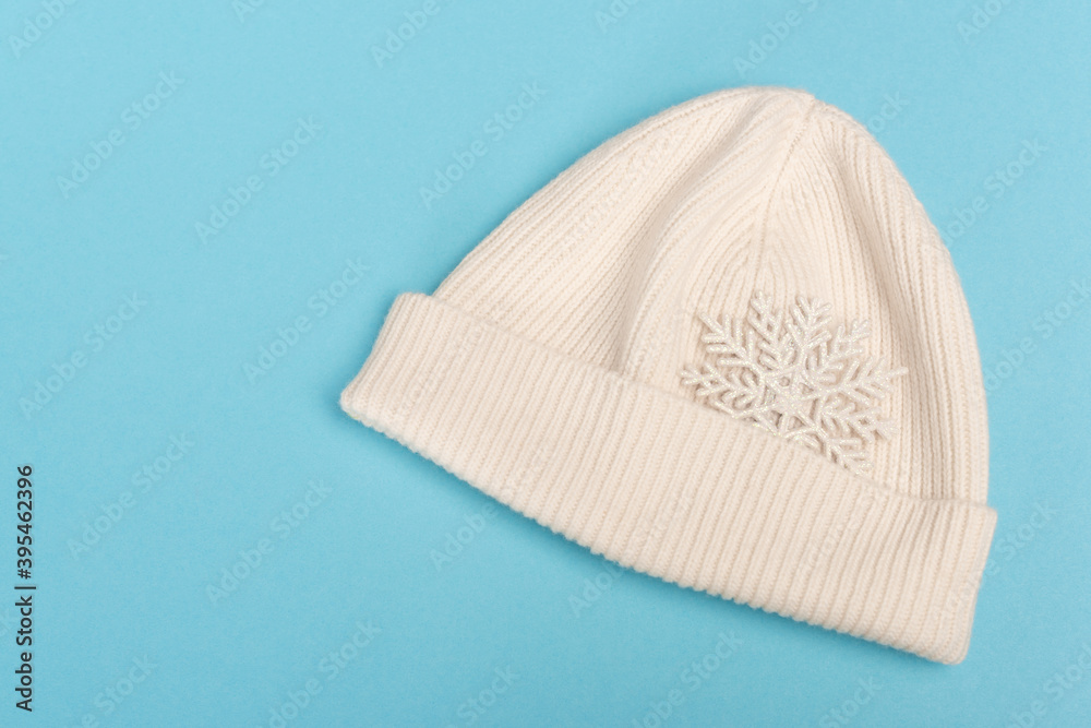 top view of white beanie and snowflake on blue top view of white beanie and snowflake on blue