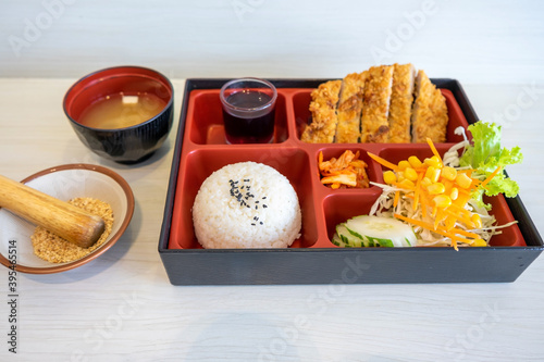 Top view of Japanese Bento Box with deep fried pork cutlet (tonkatsu set), salad and sauce. Seaweed soup