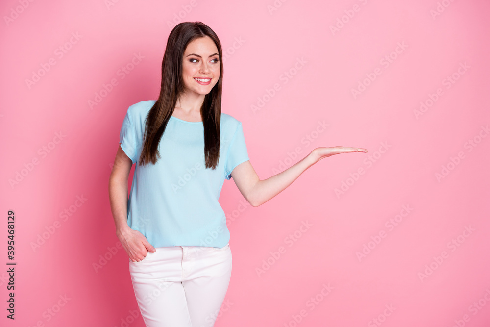 Photo of charming lady hold open arm empty space wear casual t-shirt white pants isolated pink pastel color background Photo of charming lady hold open arm empty space wear casual t-shirt white pants isolated pink pastel color background