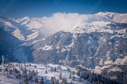 Winter landscape in the Alps. Frosty sunny day. Spruce covered with snow and frost on the background of the mountains. Ski resort Mayrhofen, Austria. Zillertal valley