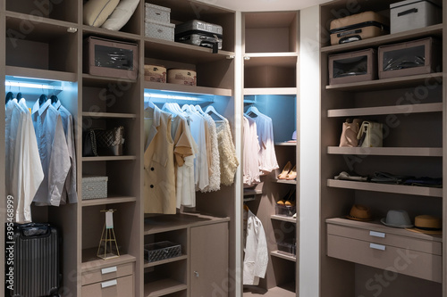 modern wooden wardrobe with clothes hanging on rail in walk in closet design interior photo