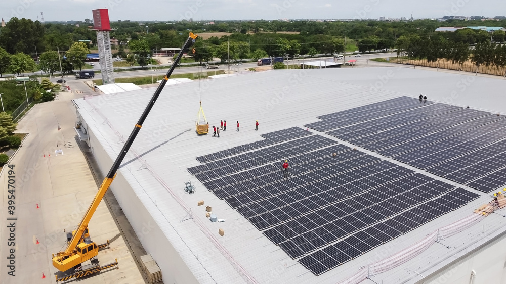 Solar panels installed on a roof of a large industrial building or a warehouse. Industrial buildings in the background. Horizontal photo. Solar panels installed on a roof of a large industrial building or a warehouse. Industrial buildings in the background. Horizontal photo.