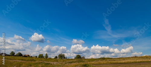 White clouds in blue sky over grass field in summer