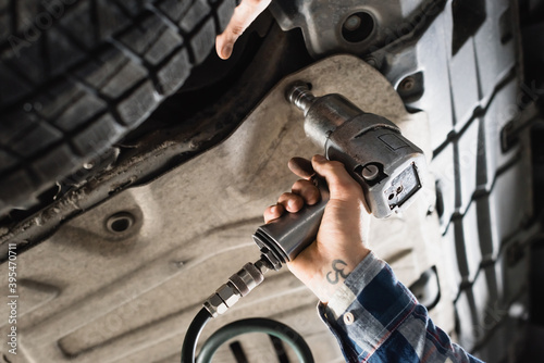 cropped of technician fixing detail of car with pneumatic wrench photo