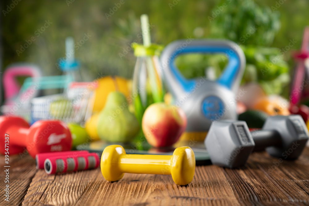 Fitness concept. Healthy nutrition: fruits and vegetables. Equipment for fitness exercises: weighing machine and dumbbells. 