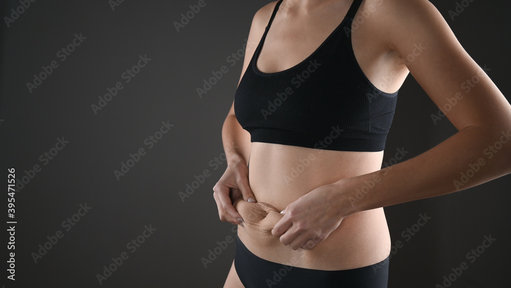 Cropped view of woman in black underwear massaging loose belly with her hands isolated on grey. Skin care and wight loss concept. Cropped view of woman in black underwear massaging loose belly with her hands isolated on grey. Skin care and wight loss concept.