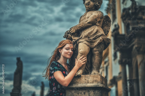 beautiful fashion model near an angel statue. © jozefklopacka