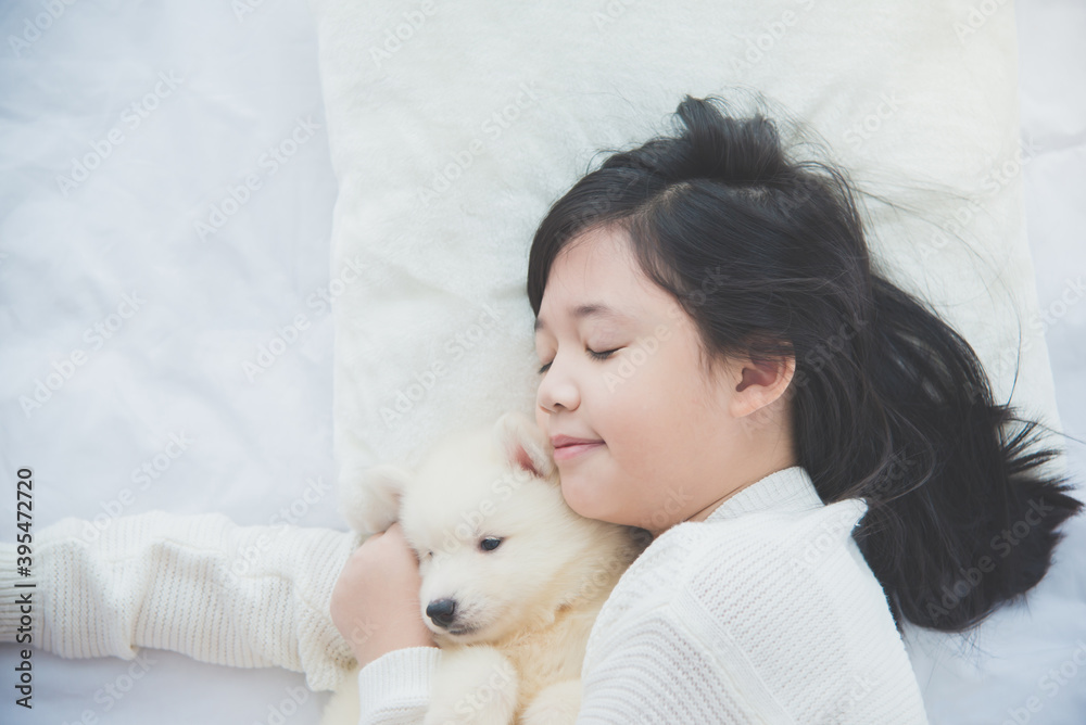 asian girl lying with siberian husky puppy on bed.. asian girl lying with siberian husky puppy on bed..