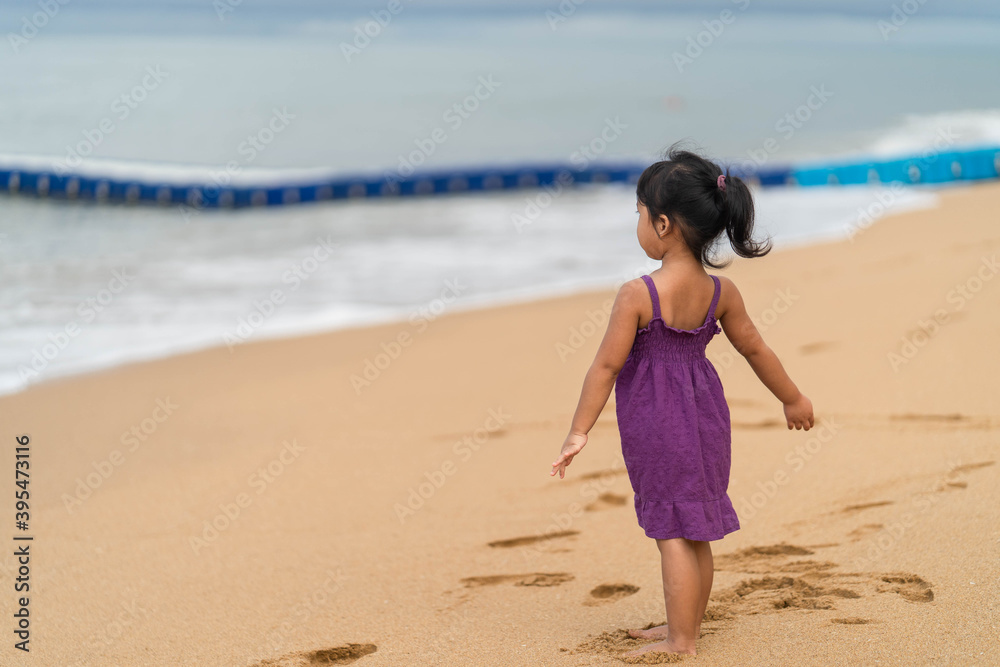 Cute little girl playing on the beach in morning.