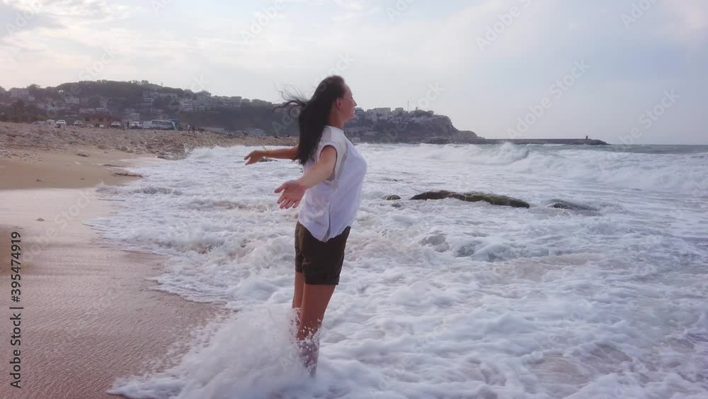 Young brunette girl stands on sandy seashore. woman walks along sandy beach Young brunette girl stands on sandy seashore. woman walks along sandy beach