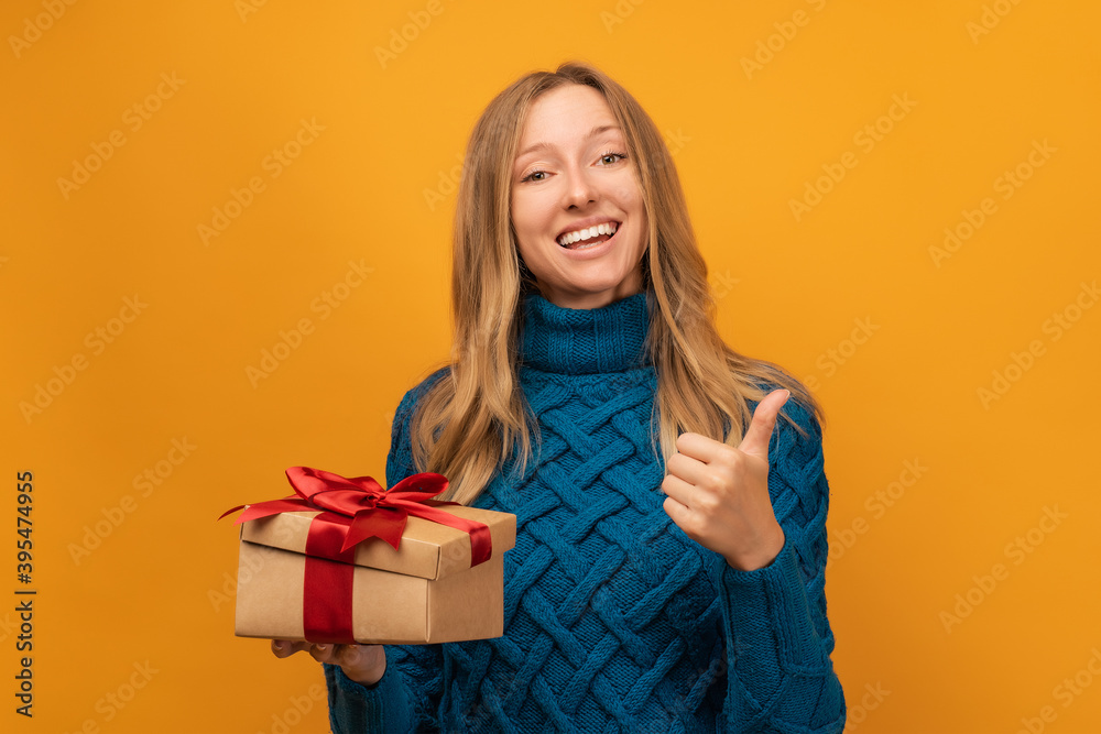 Charming young woman open a gift with red ribbon. Studio shot, yellow background. New Year, Birthday, Holiday concept Charming young woman open a gift with red ribbon. Studio shot, yellow background. New Year, Birthday, Holiday concept