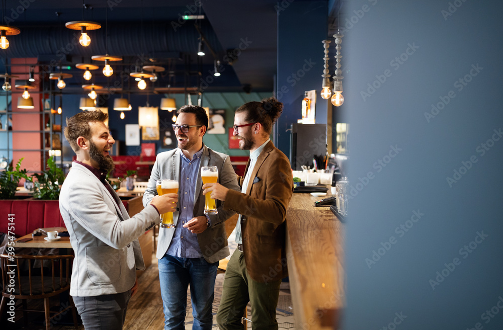 Happy young business men talking and drinking beer in a pub