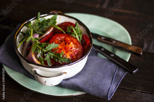 Ceramic bowl full of salad of organic vegetables like a tomato, red onion, rocket herb and flax seed photo