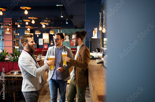 Happy young business men talking and drinking beer in a pub