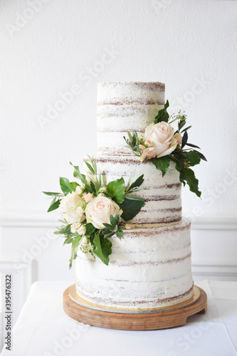 A naked three-tier wedding cake decorated with roses photo