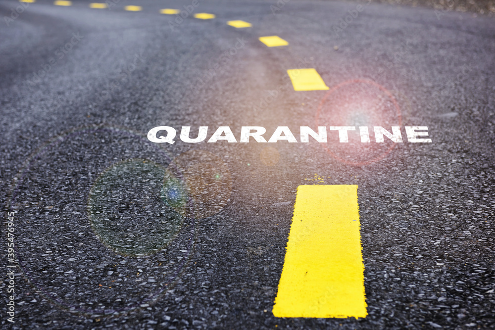 Quarantine written on asphalt road with marking lines for giving directions. Covid-19 concept and new normal protection idea