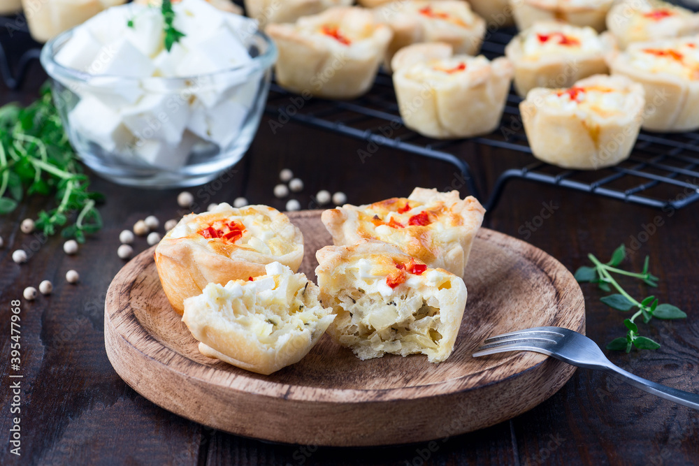 Feta cheese and fried onion mini quiche muffins, on wooden plate and cooling rack, horizontal Feta cheese and fried onion mini quiche muffins, on wooden plate and cooling rack, horizontal