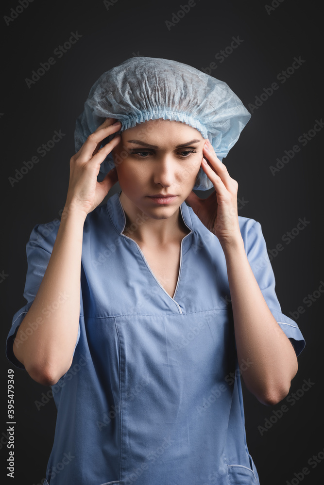 nurse in medical cap suffering from migraine isolated on dark grey nurse in medical cap suffering from migraine isolated on dark grey