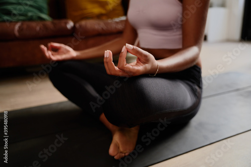 Closeup of hands of young woman sitting in lotus position meditating in the lotus pose at home