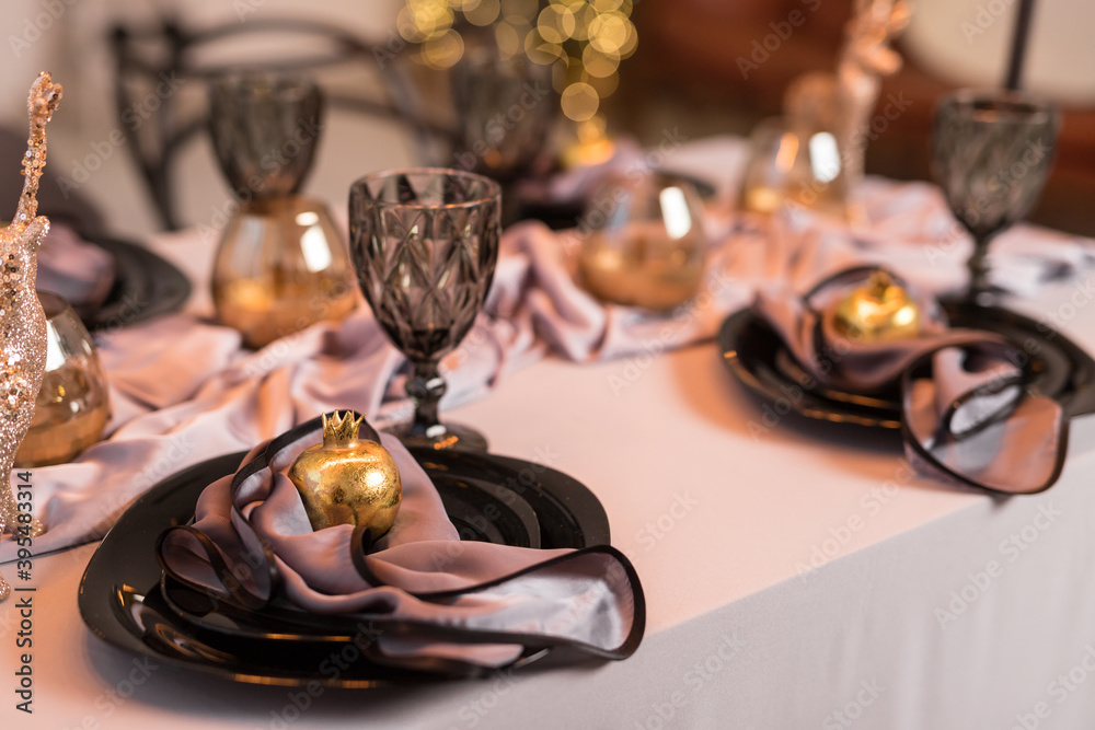 Close up of festive Christmas table setting with empty wine glasses and black plate with gold garnet Close up of festive Christmas table setting with empty wine glasses and black plate with gold garnet