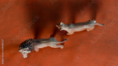 plastic figurines of couple of lions on orange background