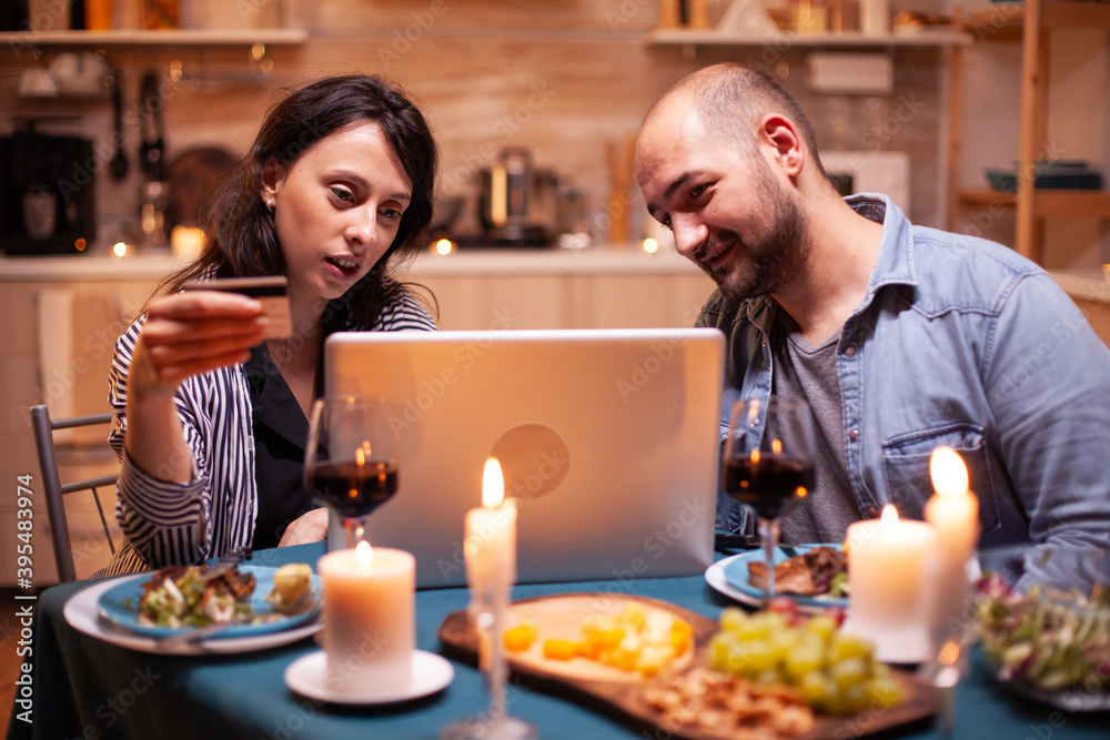Husband and wife making online payment during romantic dinner. Adults sitting at the table, searching, browsing, surfing, using technology card payment, internet. Husband and wife making online payment during romantic dinner. Adults sitting at the table, searching, browsing, surfing, using technology card payment, internet.