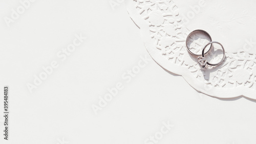 Top view on wedding and engagement rings with diamond on laced napkin. Symbol of love and marriage on white background. Sunlight on white background. photo