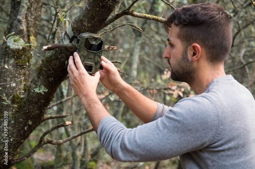 A forester installs a photographic camera trap with infrared radiation and a motion detector in a tree, they photograph animals in the Mediterranean forest. photo