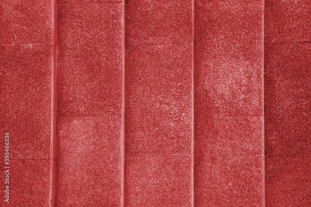 Fototapeta premium Large red textured concrete wall with vertical lines and a pattern of repeating dots.