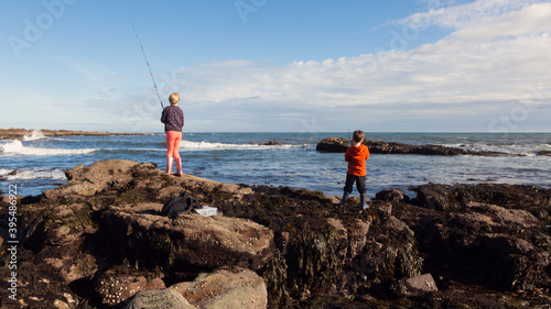 A 10yr old girl and her 6yr old brother fishing into the sea at Crail, Fife, Scotland. They love fishing (or trying to catch fish, as I call it). photo