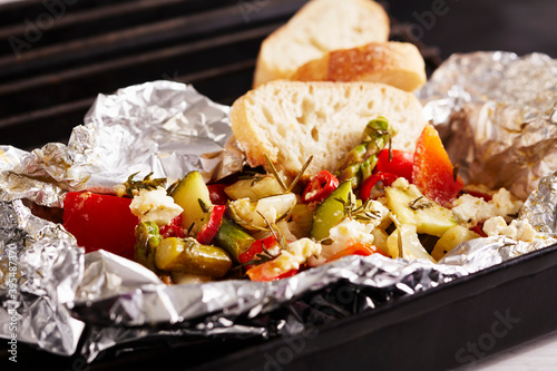 Grilled Mediterranean vegetables with a herb marinade in aluminium foil with sheep's cheese and white bread photo