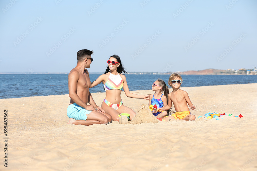 Happy family playing on sandy beach near sea. Summer holidays Happy family playing on sandy beach near sea. Summer holidays