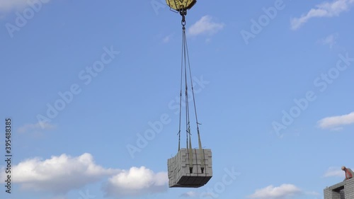 A construction crane on a background of blue sky lifts a load.4k