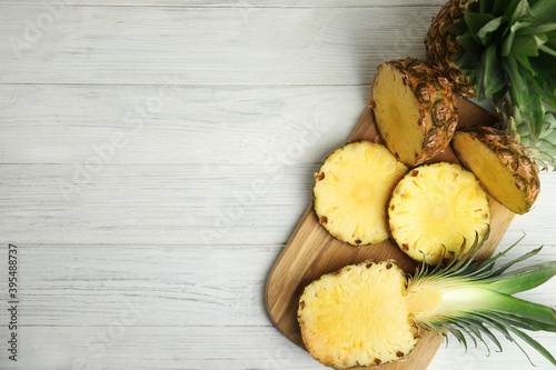 Slices of fresh pineapple on white wooden table, flat lay. Space for text