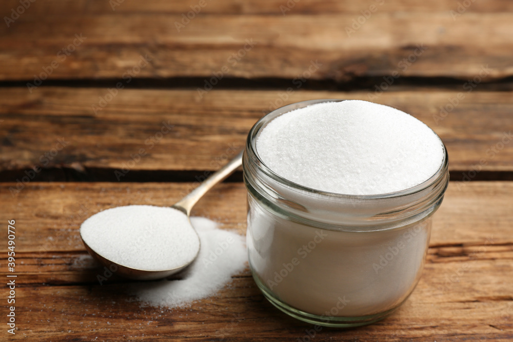 Glass jar and spoon with salt on wooden table, closeup Glass jar and spoon with salt on wooden table, closeup