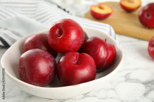Fototapeta Naklejka Na Ścianę i Meble -  Delicious ripe plums in bowl on white marble table