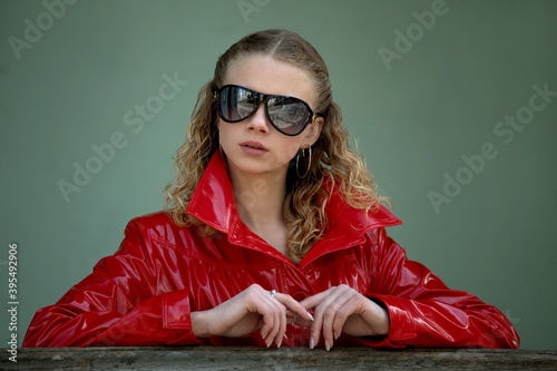 portrait of a beautiful girl in dark sunglasses and a bright shiny red cloak