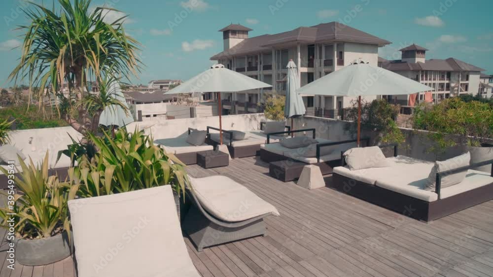 Camera Dolly shot of leisure area on terrace of posh hotel showing chase-lounge, swimming pool and greenery Camera Dolly shot of leisure area on terrace of posh hotel showing chase-lounge, swimming pool and greenery