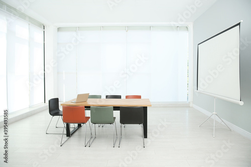 Conference room interior with wooden table and video projection screen