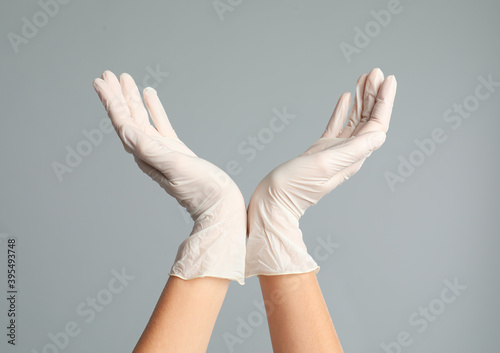 Doctor wearing medical gloves on grey background, closeup