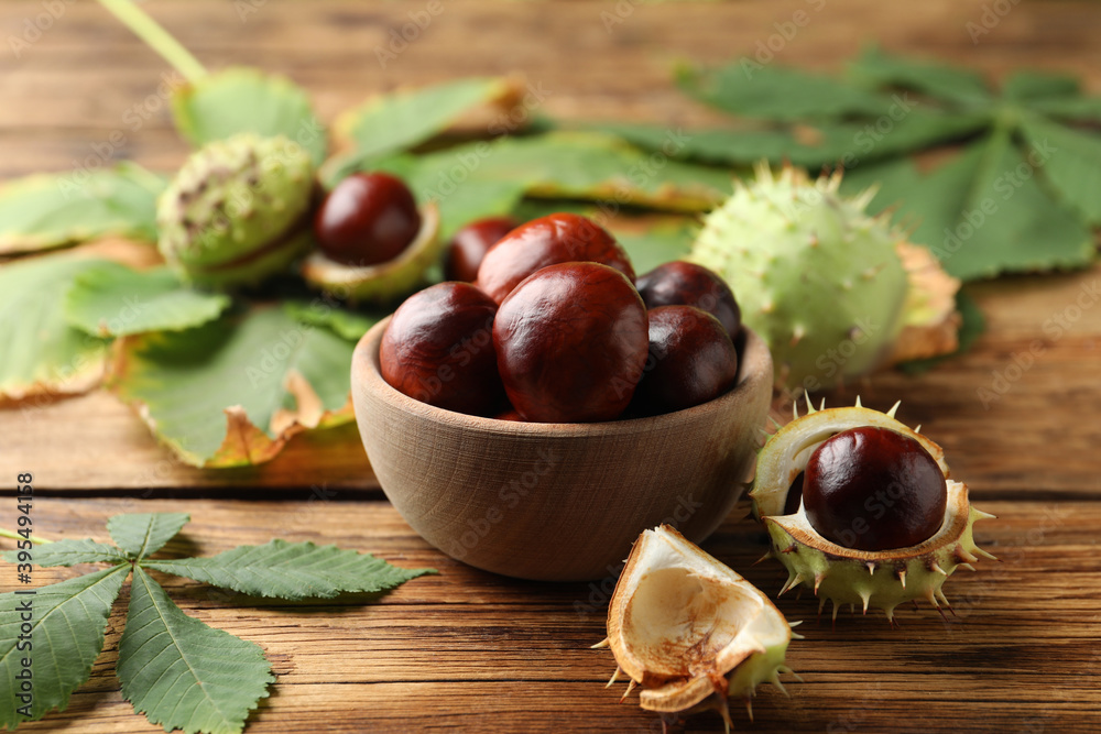 Horse chestnuts and leaves on wooden table Horse chestnuts and leaves on wooden table