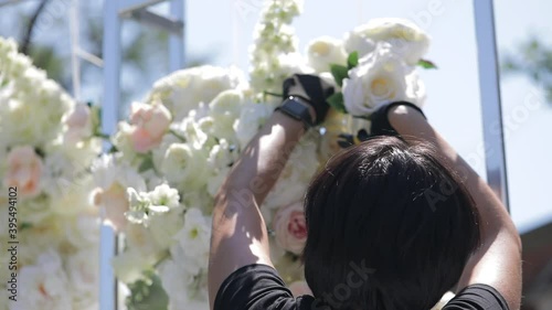 The florist decorates the wedding arch with fresh flowers