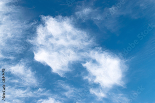 White feathery fluffy clouds on a blue sky, background and texture