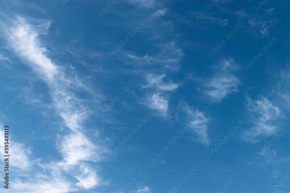 White feathery fluffy clouds on a blue sky, background and texture